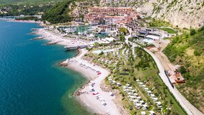 An aerial view of a coastal resort with a beach, marina, and hillside buildings. - Sea-view Penthouse Spa in Portopiccolo (Duino-Aurisina)
