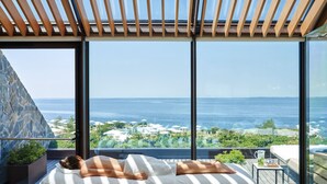 A spa room with a large window overlooking the sea, a wooden ceiling, and a massage table with a towel. - Sea-view Penthouse Spa in Portopiccolo (Duino-Aurisina)