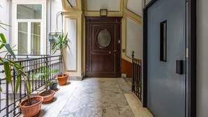A hallway with a marble floor, potted plants, a wooden door, and a window with blinds. - Rosaroll 70 Apartment by Wonderful Italy (Naples)