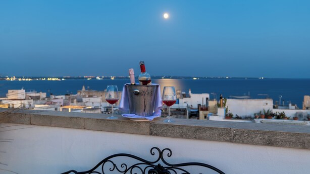 Un balcon avec vue sur la mer et une lune dans le ciel.