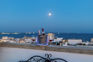 Un balcón con vista al mar y una luna en el cielo.