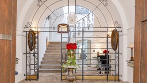 Une entrée imposante, agrémentée d’un portail en fer forgé, d’un escalier et d’un vase décoratif orné de fleurs rouges.