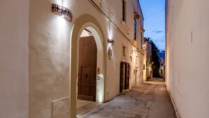 Une rue étroite, bordée de bâtiments des deux côtés, une porte en bois et une enseigne au-dessus de la porte.