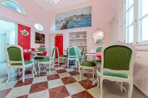 Un comedor con sillas tapizadas de verde, una mesa roja y un suelo a cuadros.