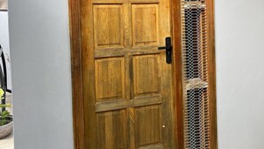 A wooden door with a metal mesh panel, a doorknob, and two wall-mounted lanterns. - Pasifika Guesthouse (Nadi)
