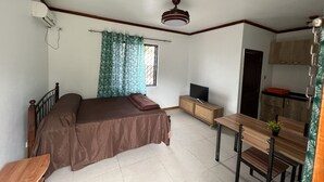 A bedroom with a bed, a TV, a desk, and a chair. - Pasifika Guesthouse (Nadi)