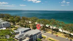 A coastal hotel with modern architecture, a road, and a beach.