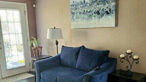 A living room with a blue sofa, a patterned rug, a painting on the wall, and a small table with a lamp. - Awesome 2 bedroom/2 bathroom townhome less than a mile from the golf course!!
 (Augusta)