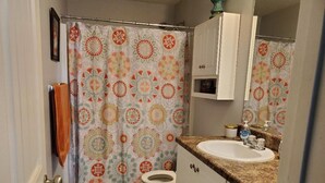 A bathroom with a patterned shower curtain, a toilet, a sink with a granite countertop, and a cabinet with a mirror above it. - Awesome 2 bedroom/2 bathroom townhome less than a mile from the golf course!!
 (Augusta)