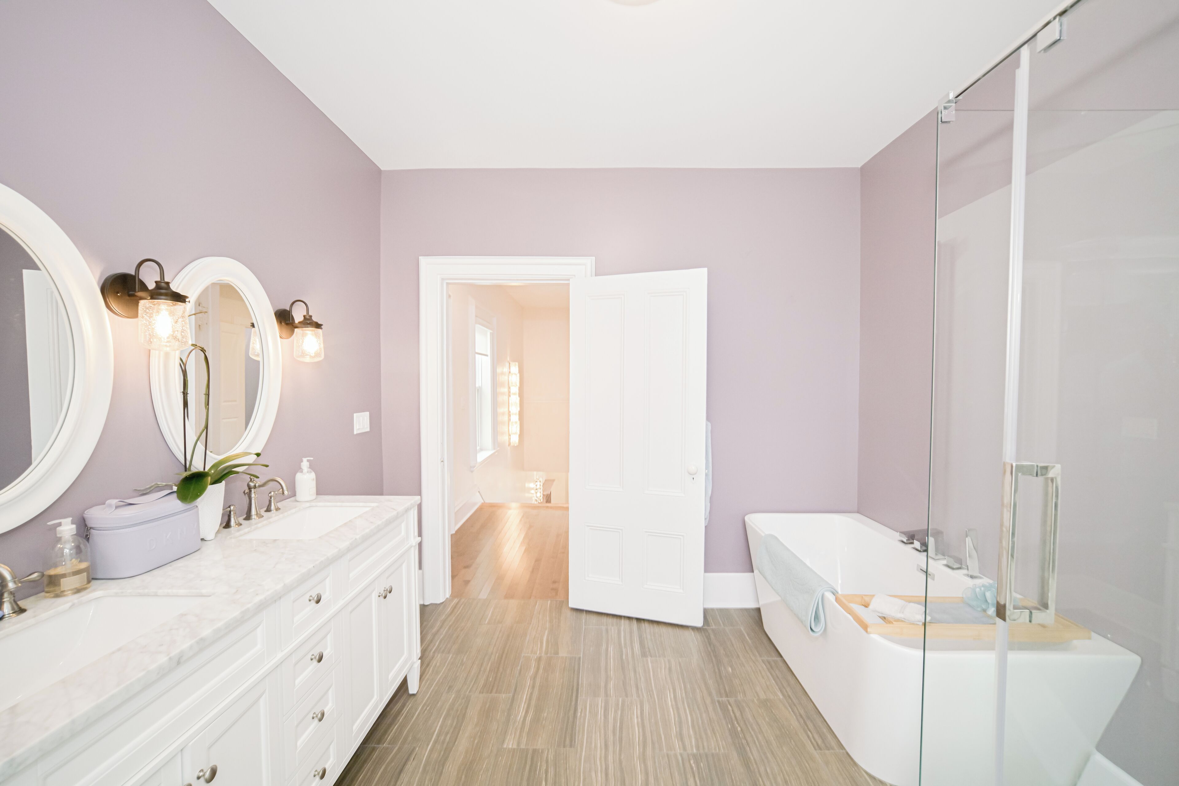A modern bathroom with a vanity, a large mirror, and a bathtub.