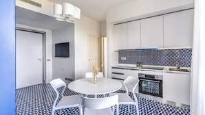 A modern kitchen with white cabinets, a patterned backsplash, and a dining area with a round table and chairs. - Le Arcate Giuliana by Feeling Italy (Massa Lubrense)