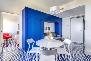 Une pièce moderne avec un mur d’accent bleu, une table ronde blanche avec des chaises et un sol à motifs.
