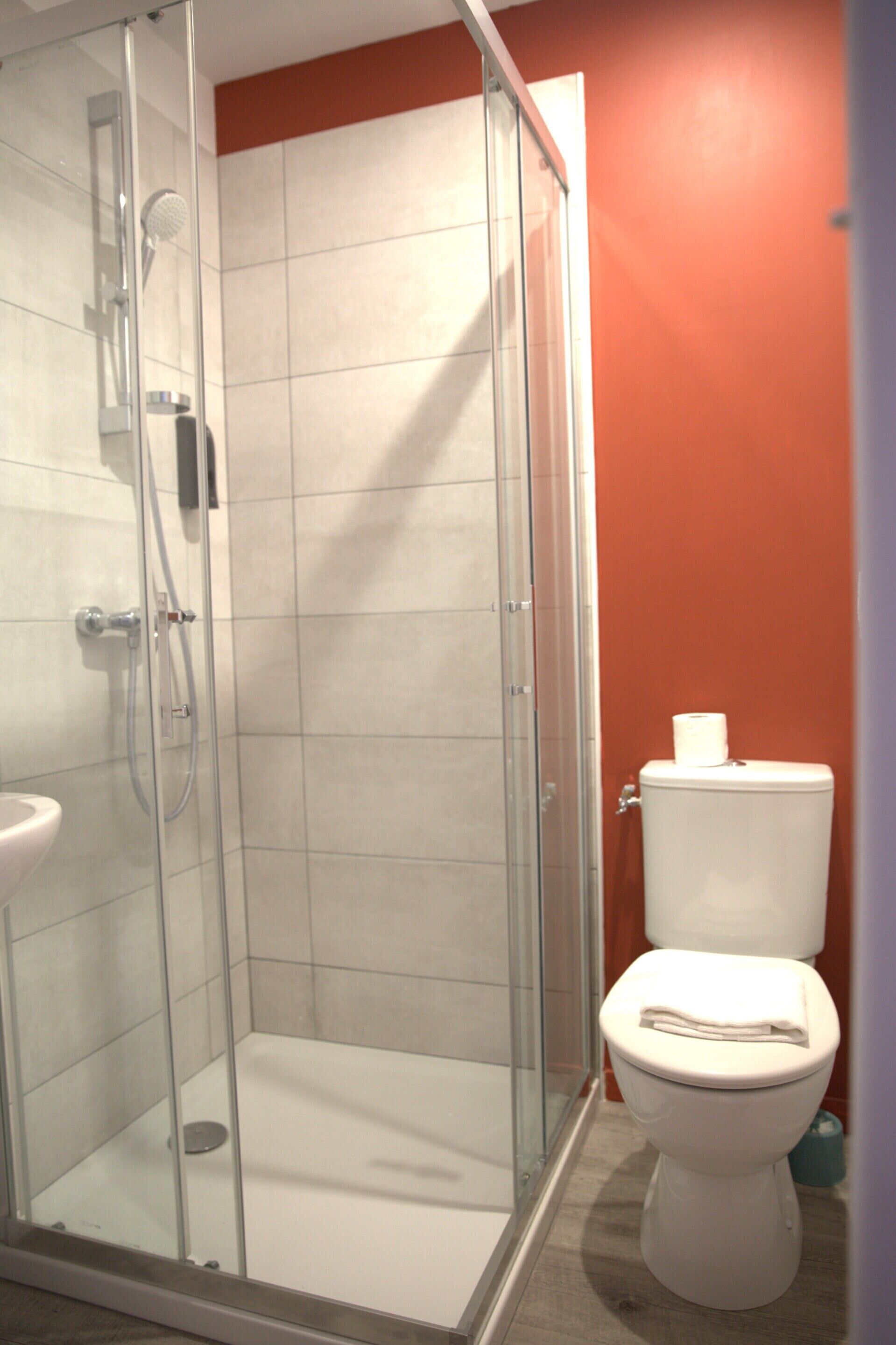 A bathroom with a glass-enclosed shower, a white toilet, and a sink.