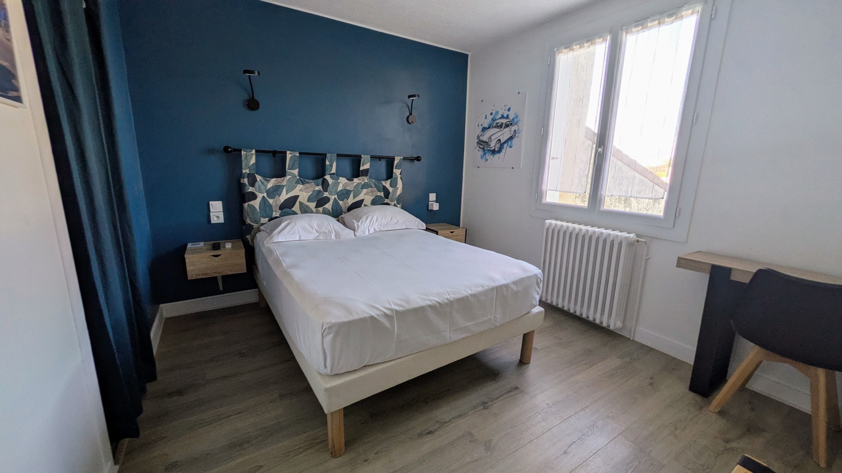A bedroom with a bed, a nightstand, a chair, a window, and a radiator.