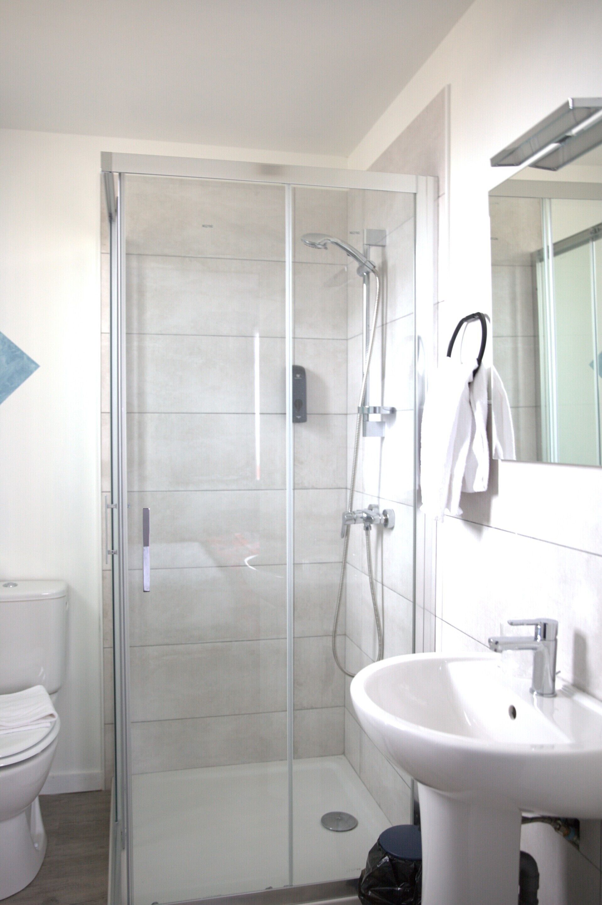 A modern bathroom with a glass-enclosed shower, a white sink, and a toilet.