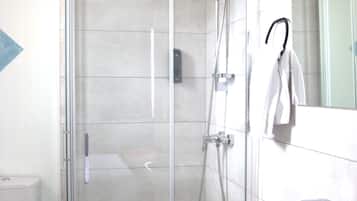 A modern bathroom with a glass-enclosed shower, a white sink, and a toilet.