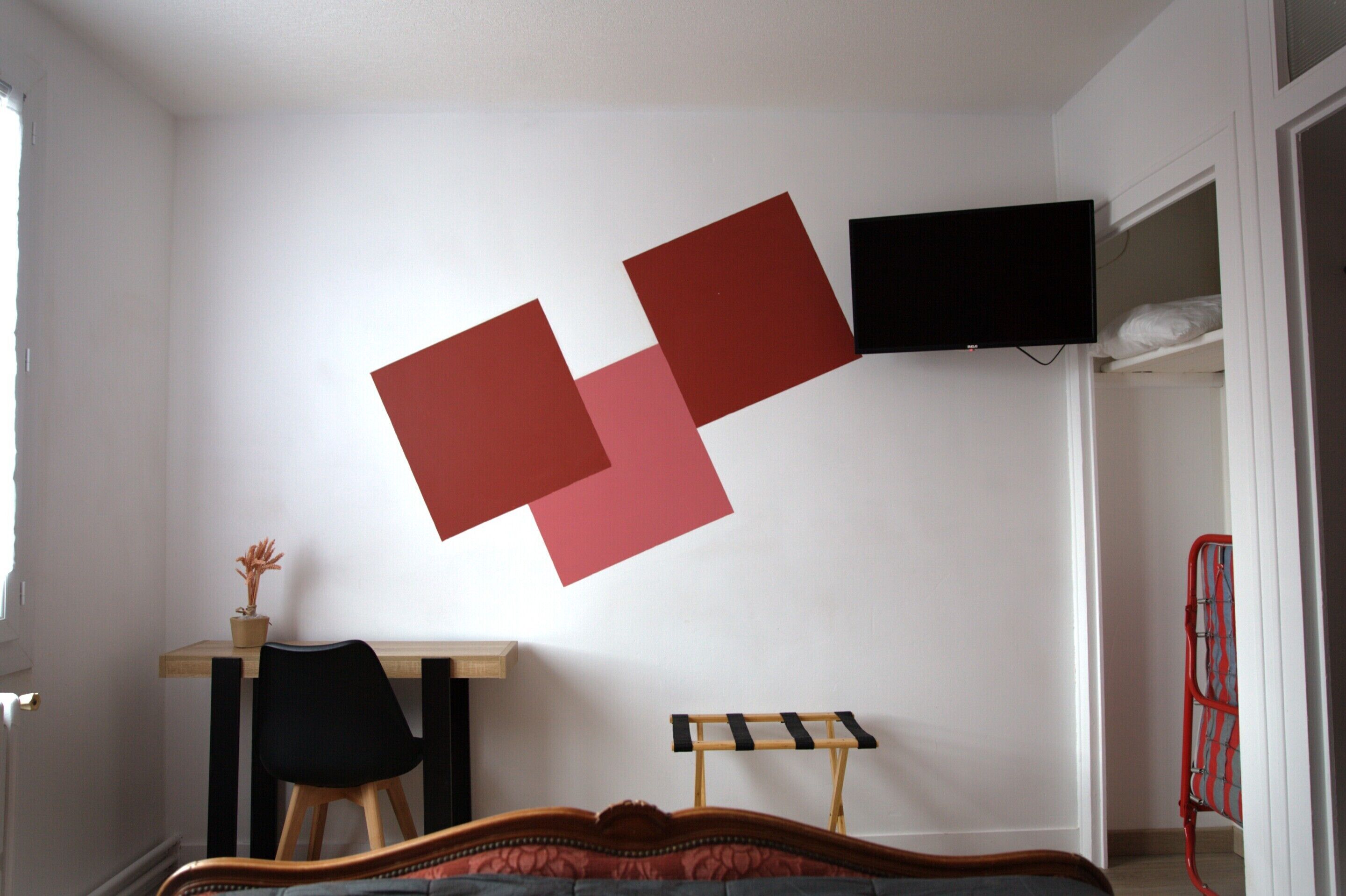 Une chambre comprenant un lit, un bureau, une chaise et un téléviseur fixé au mur.