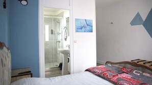 A bedroom with a bed, a bedside table, a nightstand, a bathroom with a shower, a sink, and a towel rack. - Relais 375 (Valence-en-Poitou)