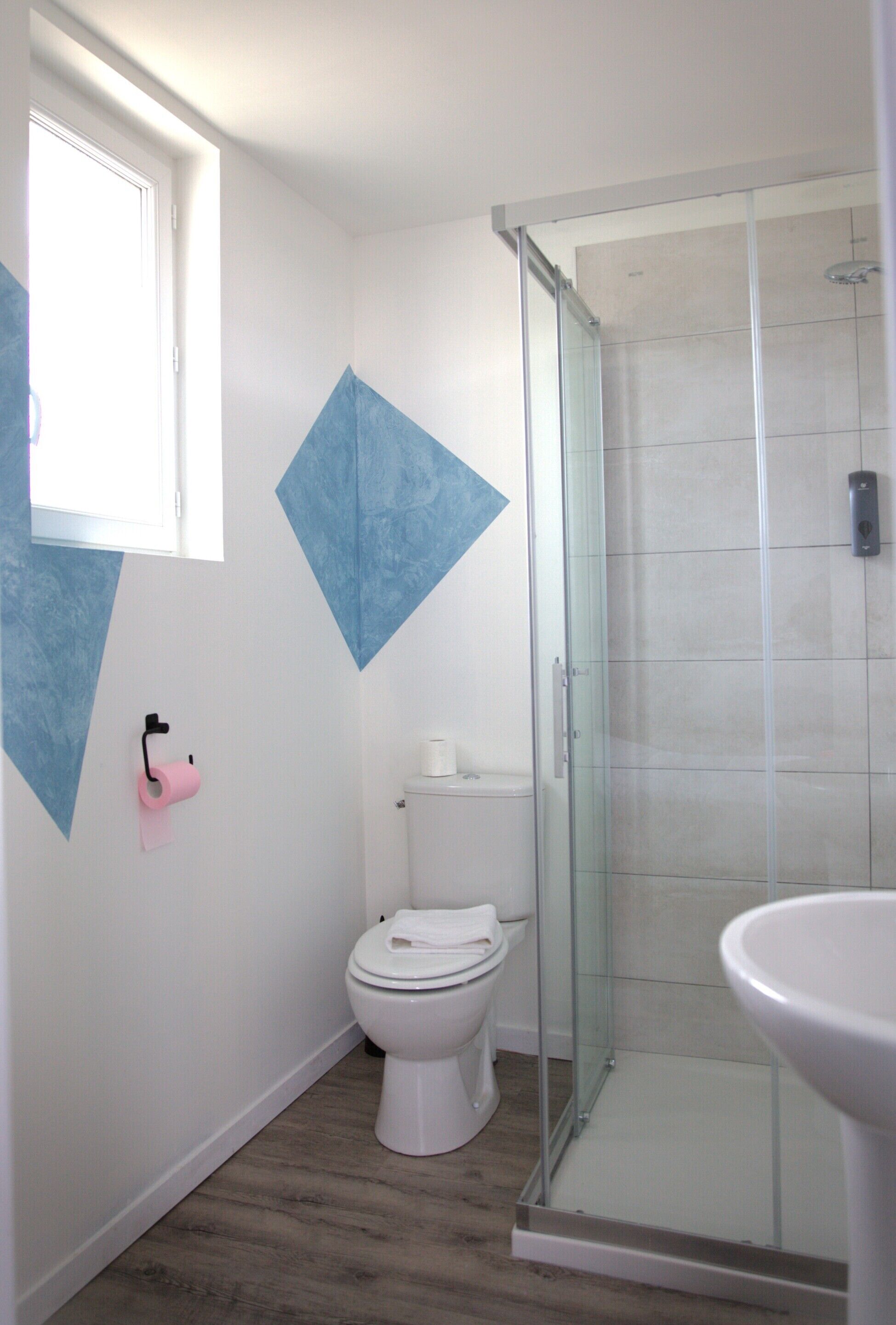 A bathroom with a toilet, a glass shower enclosure, and a sink.