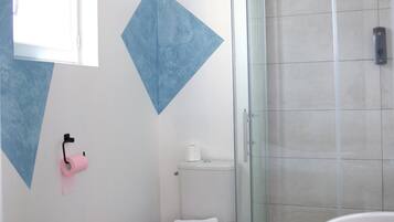 A bathroom with a toilet, a glass shower enclosure, and a sink.