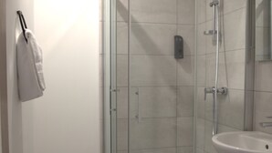 A modern bathroom with a glass-enclosed shower, a white sink, and a towel hanging on the wall. - Relais 375 (Valence-en-Poitou)