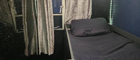 Habitació amb un llit, cortines i una finestra.
