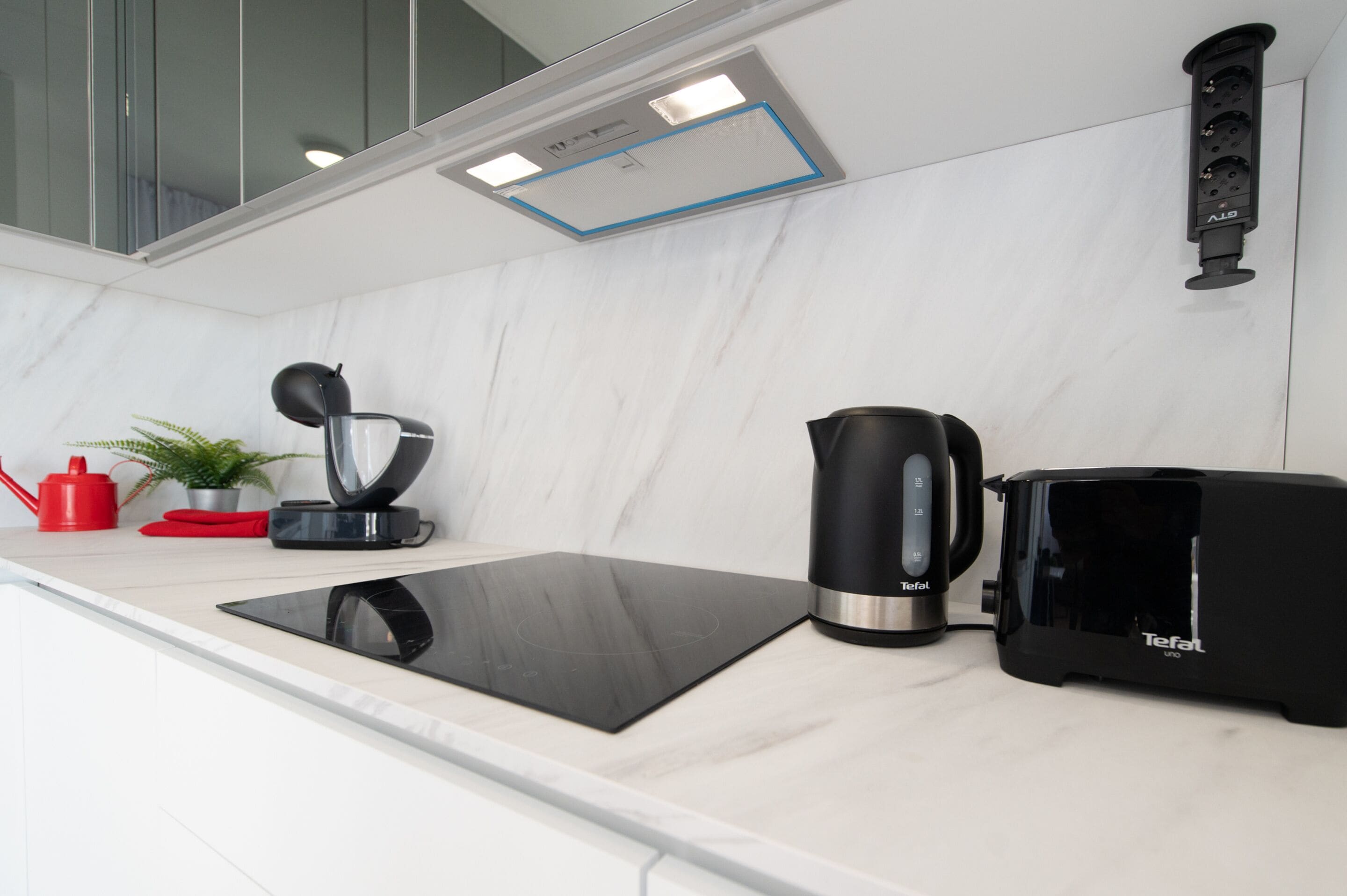 A modern kitchen with a black induction cooktop, a black coffee maker, and a black toaster.