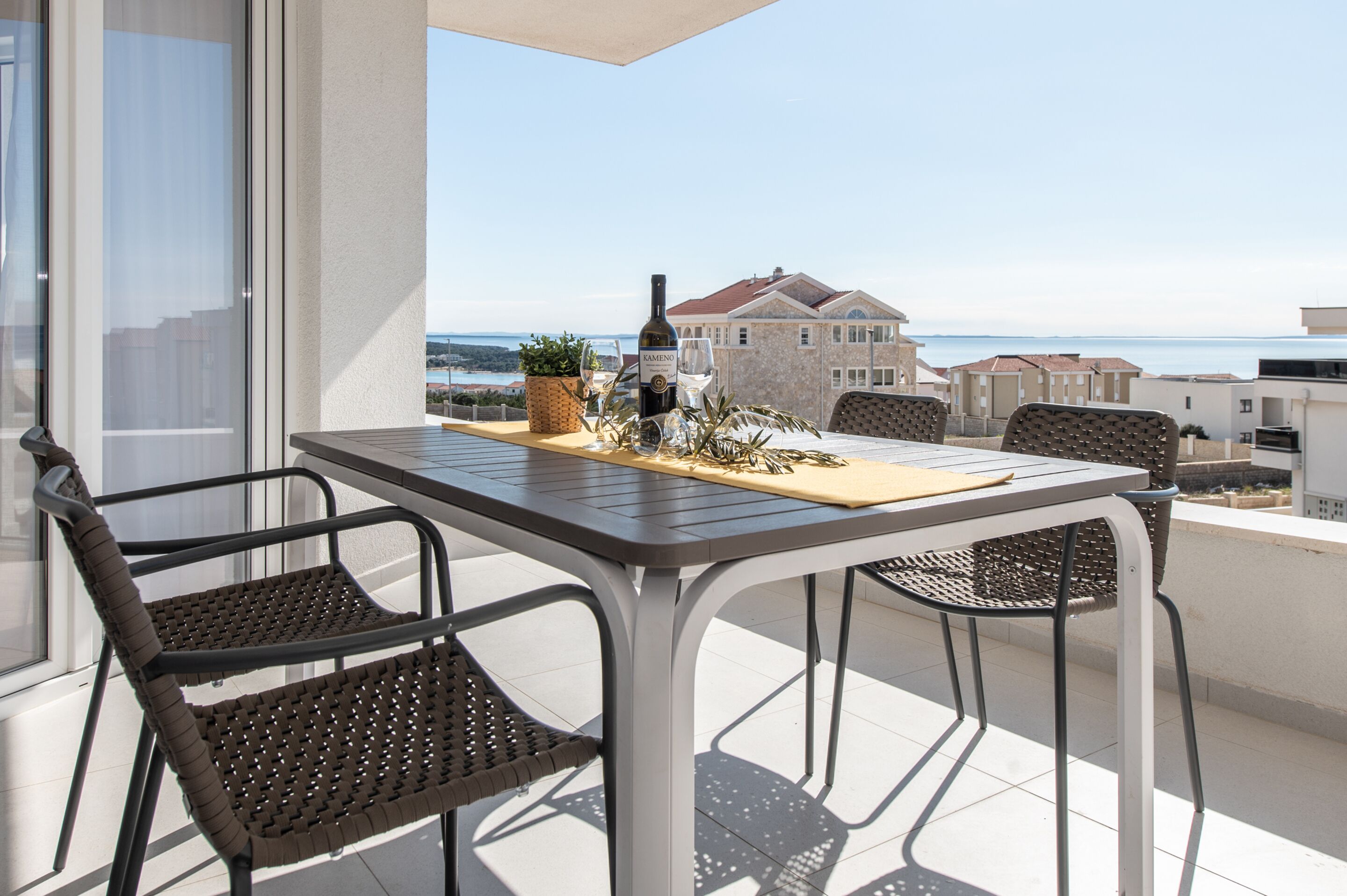 A balcony with a table and chairs, a bottle of wine, and a glass.