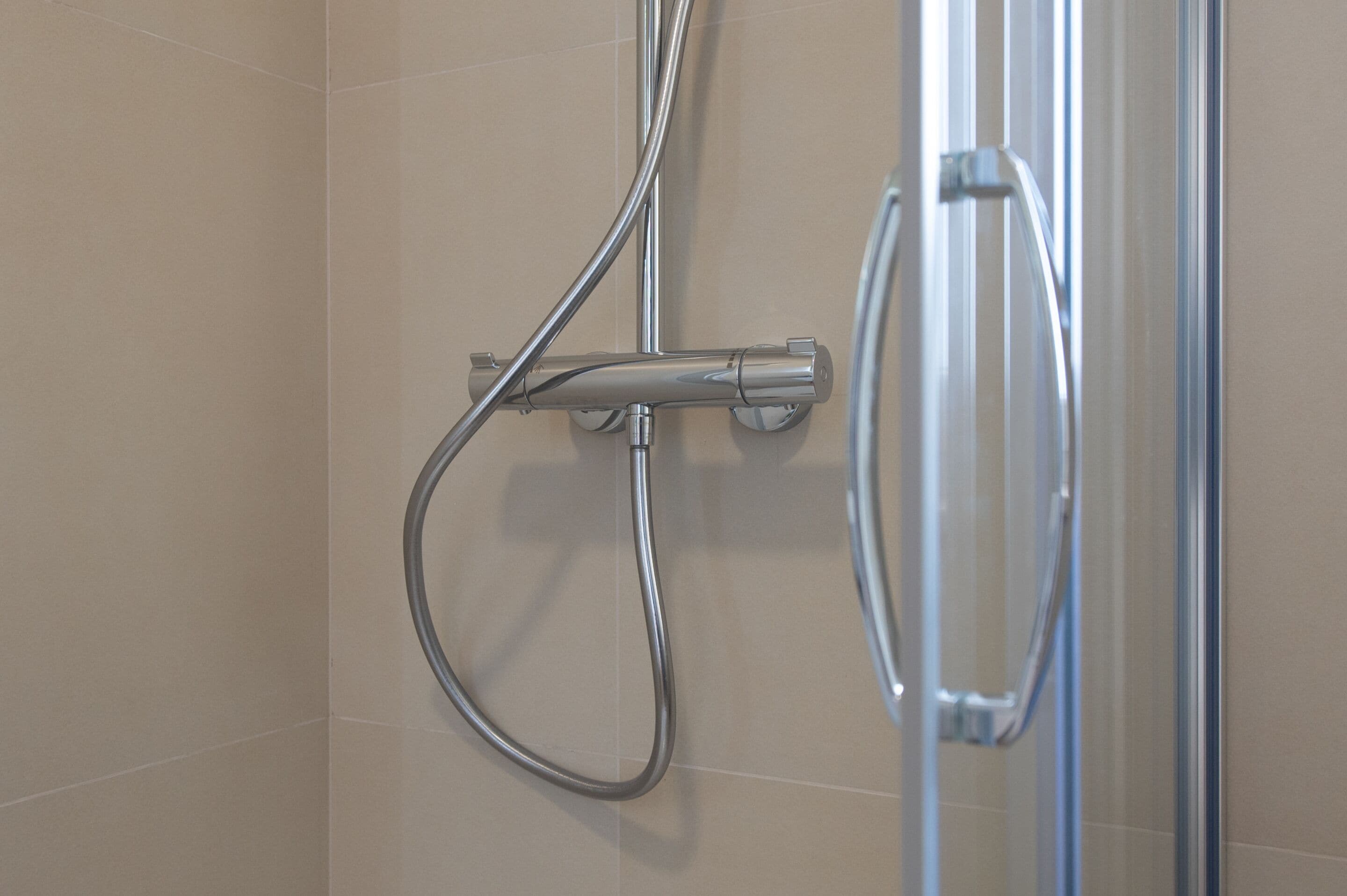 A shower with chrome fixtures and a glass door.