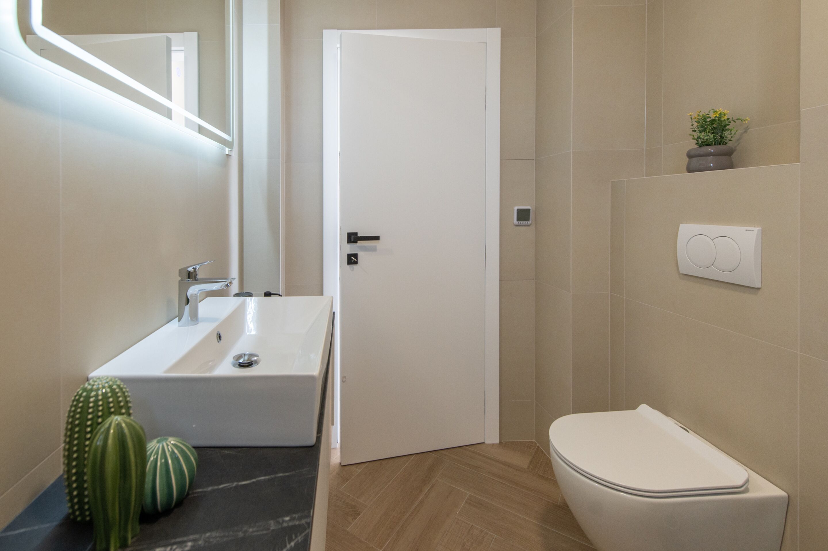 A modern bathroom with a white sink, toilet, and door.