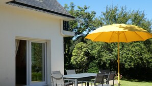A patio with a table and chairs, a yellow umbrella, and a sliding glass door.