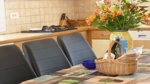 A dining area with a table set for four, a vase with flowers, and a basket with bread.