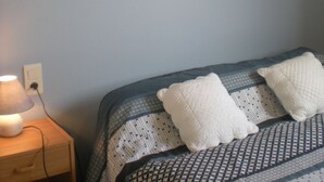 A bedroom with a bed, a nightstand, a lamp, and wall art.