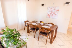 A dining area with a wooden table set for four, surrounded by chairs. - Villa III (St. George's)