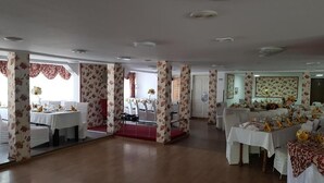 A spacious hall with multiple tables set for dining, featuring floral patterns on the walls and columns. - CASA SIADY (Vatra Dornei)