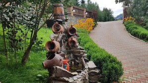 A garden with a stone wall, terracotta pots, and a brick pathway. - CASA SIADY (Vatra Dornei)