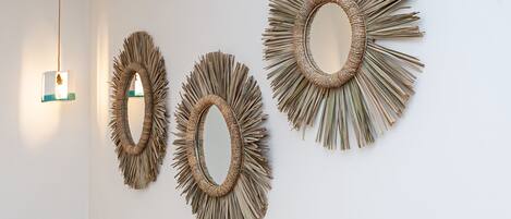 Tres espejos montados en la pared con un diseño natural y tejido.