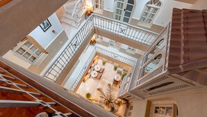 A multi-level courtyard with a central seating area, white railings, and arched windows. - Riad k-white (Marrakech)