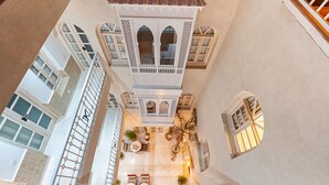 A courtyard with a central seating area, a decorative tower, and multiple windows. - Riad k-white (Marrakech)