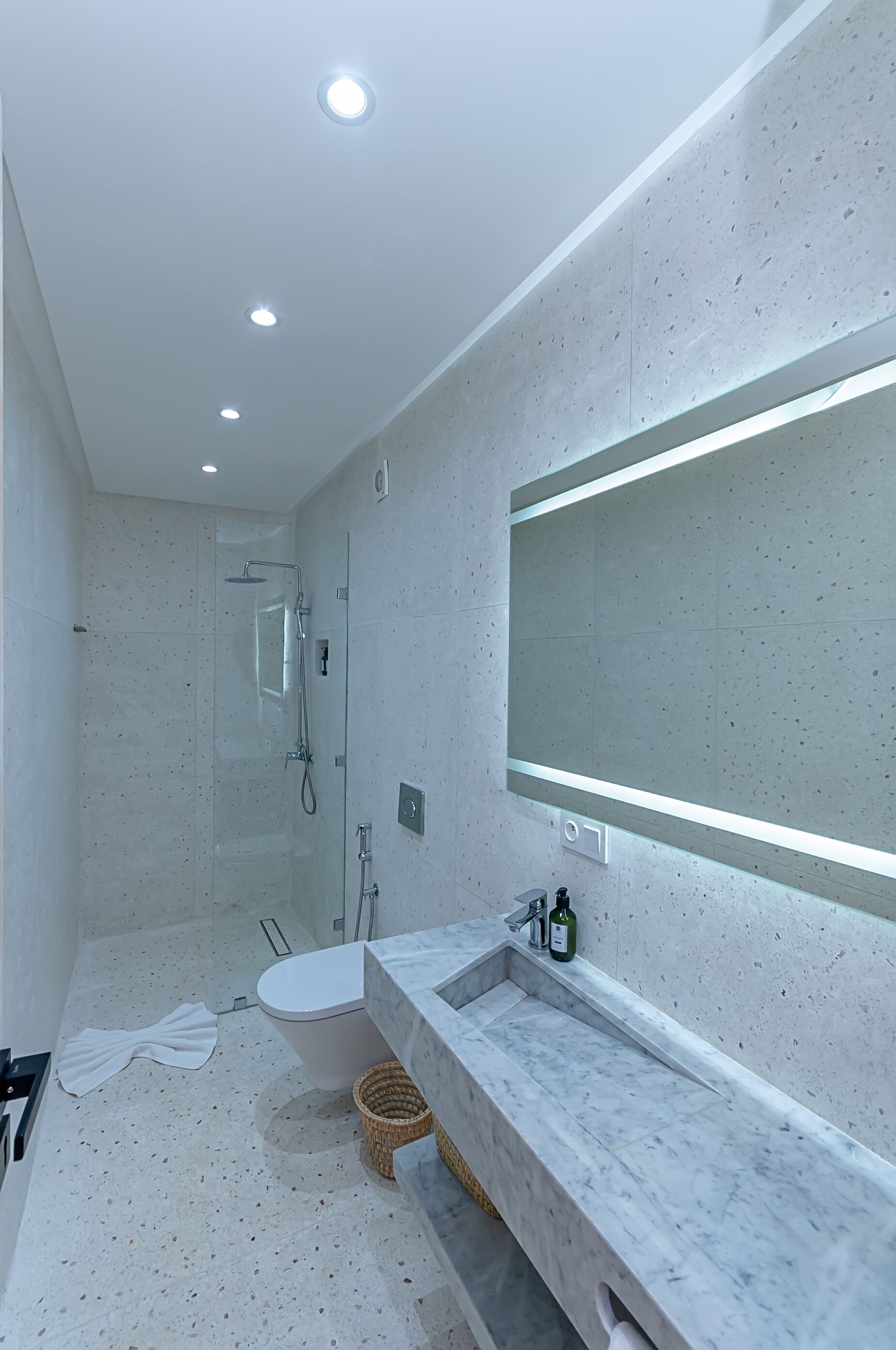 Un baño moderno con un espejo grande, una bañera y una zona de ducha.