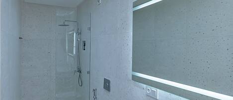 Un baño moderno con un espejo grande, una bañera y una zona de ducha.