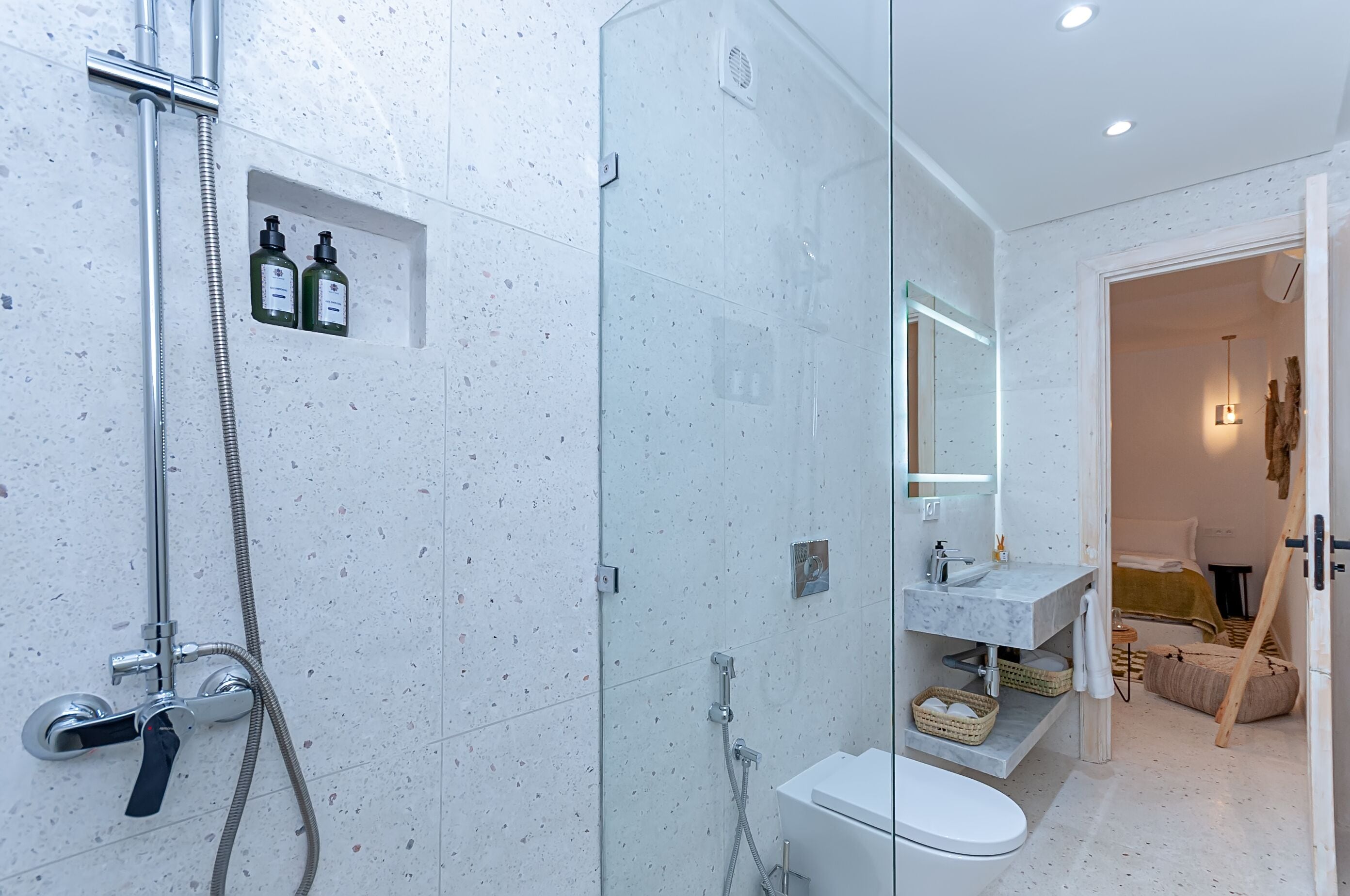 Un baño moderno con cabina de ducha de vidrio, inodoro blanco y tocador con espejo.