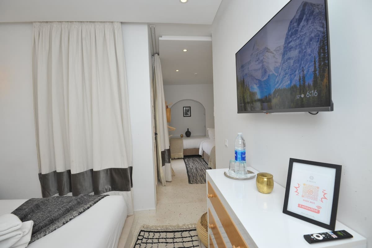 Une chambre d’hôtel avec un lit, un bureau doté d’une télécommande, un certificat encadré et un tableau représentant des montagnes accroché au mur.