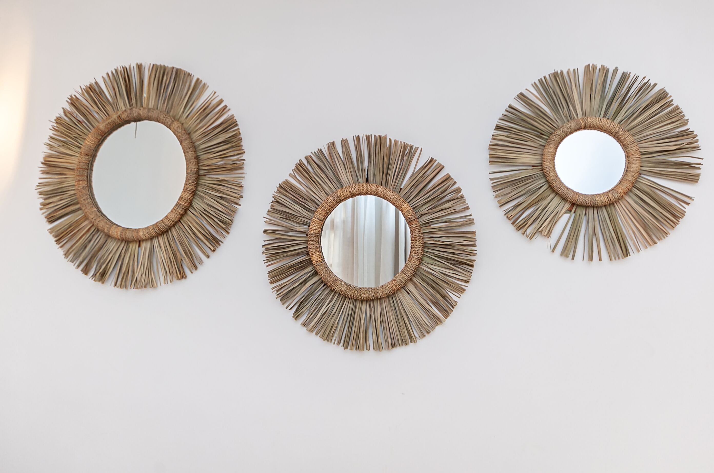 Three wall-mounted mirrors with a sunburst design.