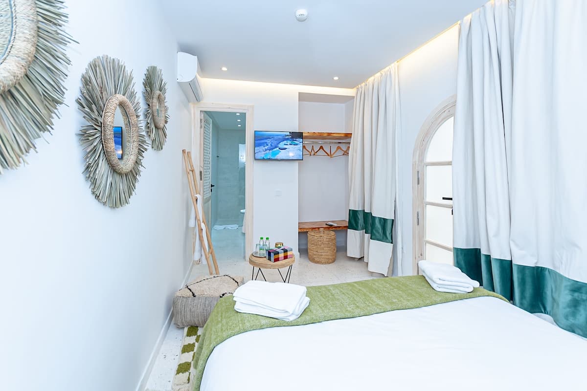 Une chambre d’hôtel équipée d’un lit, d’une télévision, d’une armoire et d’une petite table avec des articles de toilette.