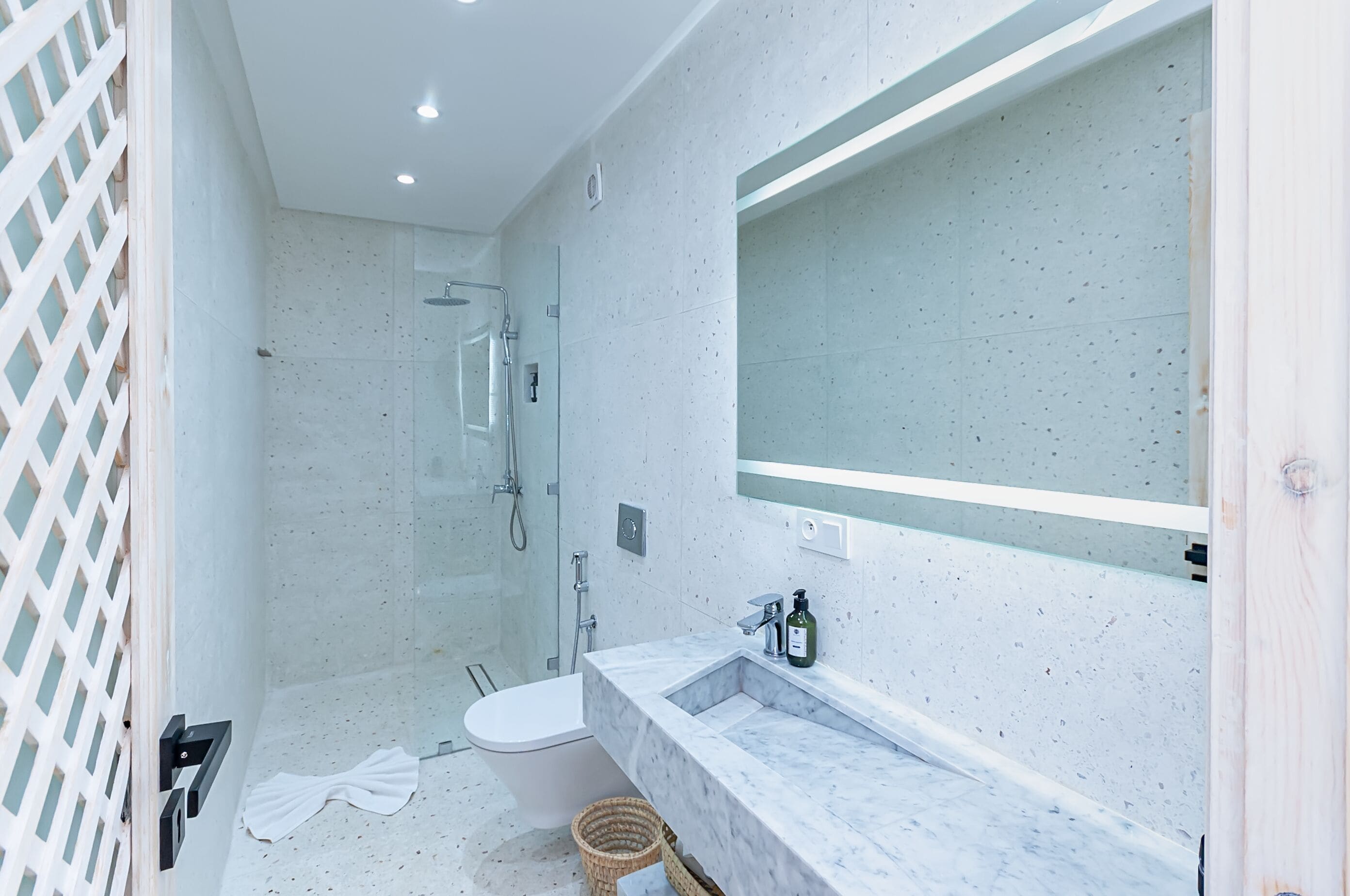 A modern bathroom with a glass-enclosed shower, a white toilet, and a marble sink.