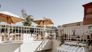 A multi-level outdoor terrace with white railings, beige umbrellas, and arched windows. - Riad k-white (Marrakech)