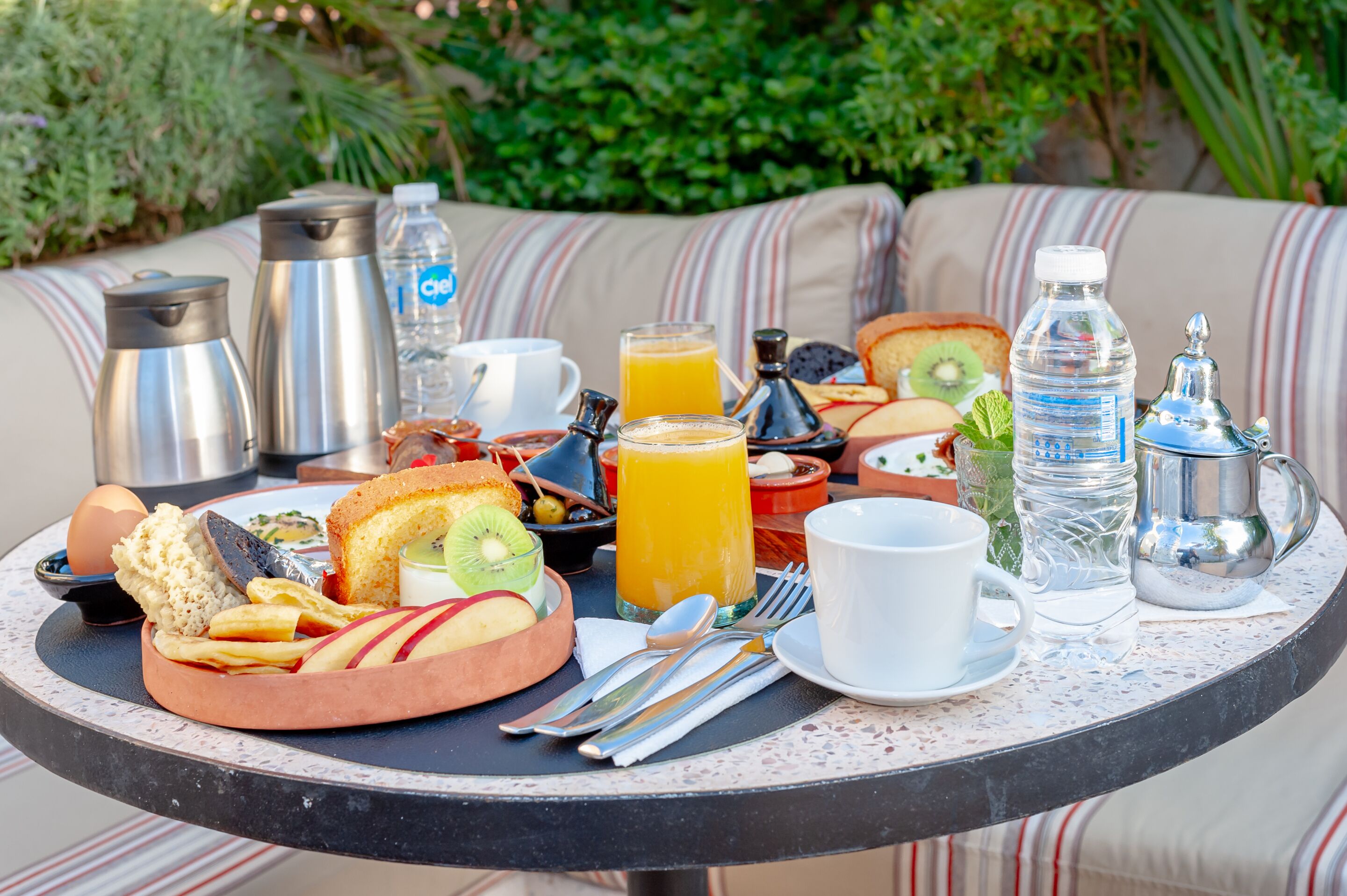 Una mesa redonda con una variedad de alimentos, bebidas y utensilios para el desayuno.