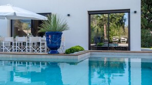 A modern pool area with a large blue planter, outdoor seating, and a view of the surrounding greenery. - Onda 8, Emma Villas - Four Bedroom Villa, Sleeps 8 (Scacciano)