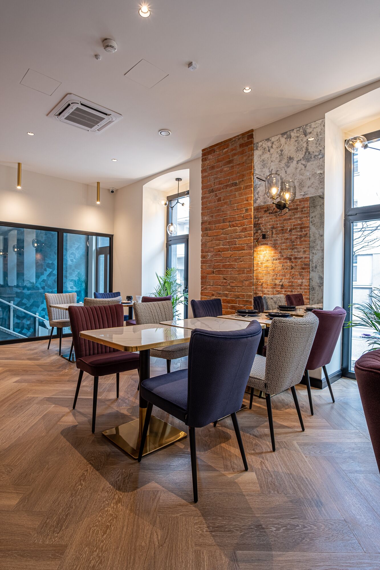 A modern dining area with a brick accent wall, wooden flooring, and contemporary furniture.
